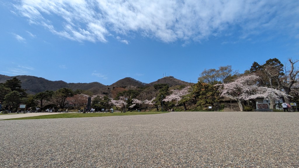 View of Mt. Hakodate from the wide plaza at Hakodate Park with cherry trees.