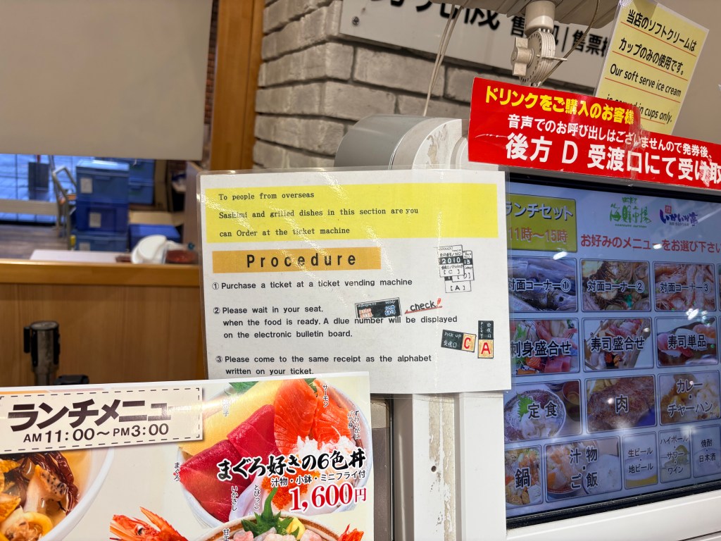 A close-up of a yellow sign titled "Procedure" with English instructions for ordering food at a ticket machine.