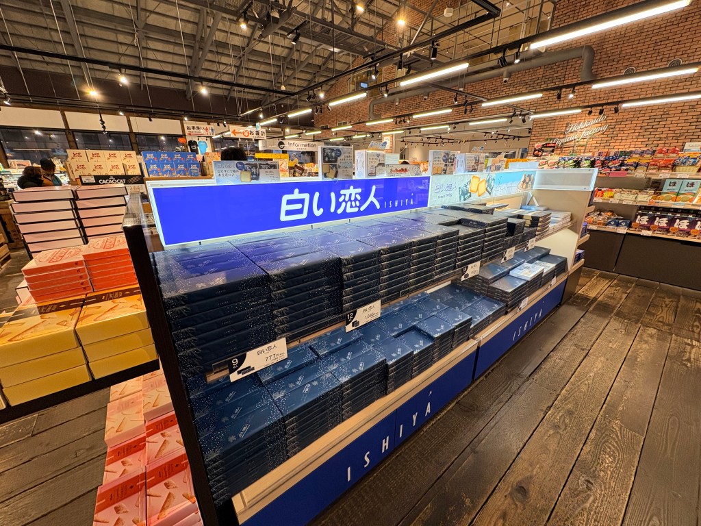 A blue display shelf filled with various sizes of Shiroi Koibito cookie boxes.