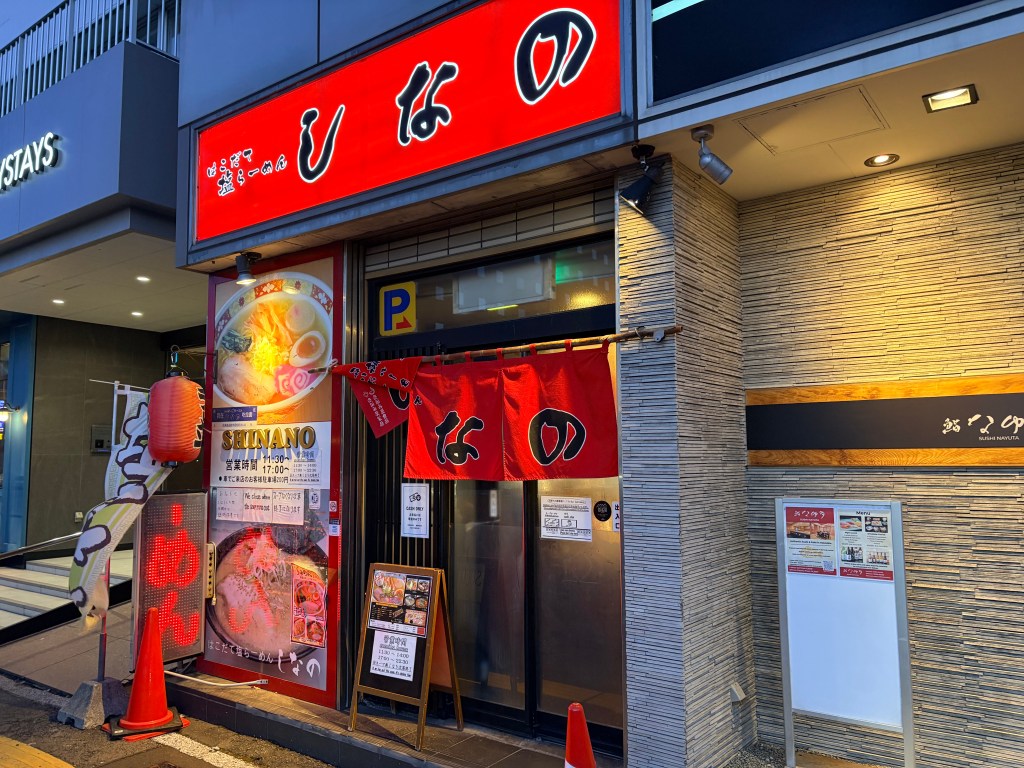 The exterior of Shinano Ramen with a bright red curtain and lanterns at the entrance.