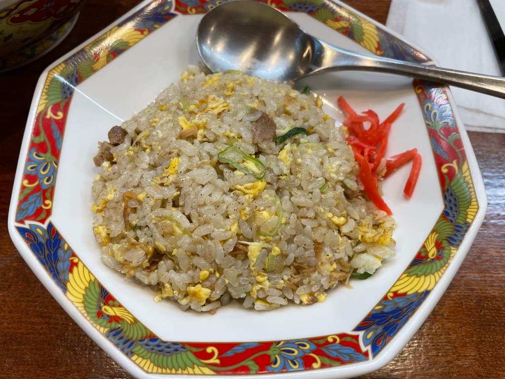 A plate of savory fried rice topped with red pickled ginger.