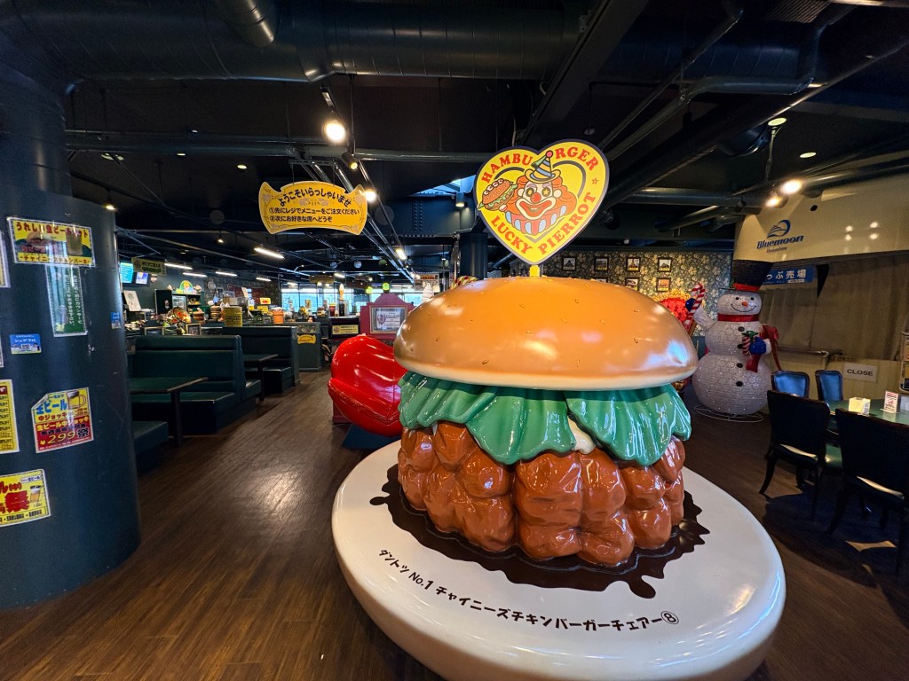 A large, colorful statue of a hamburger shaped like a chair inside the restaurant.