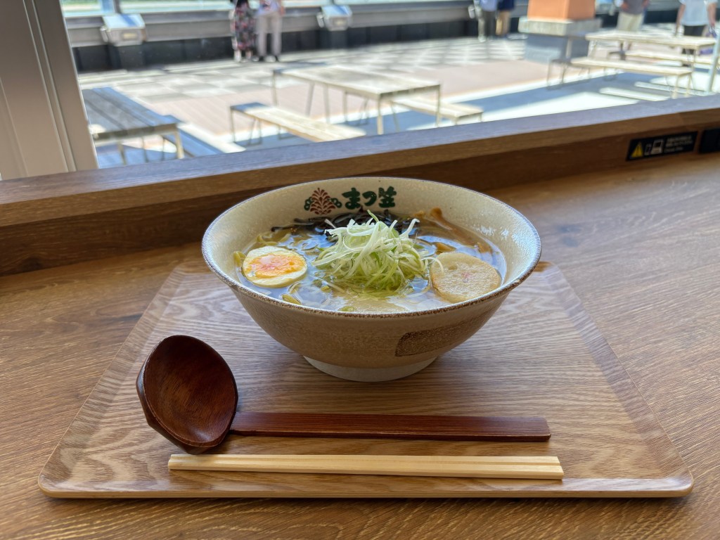 A bowl of traditional Hakodate Salt (Shio) Ramen with clear broth, bamboo shoots, green onions, and a soft-boiled egg.