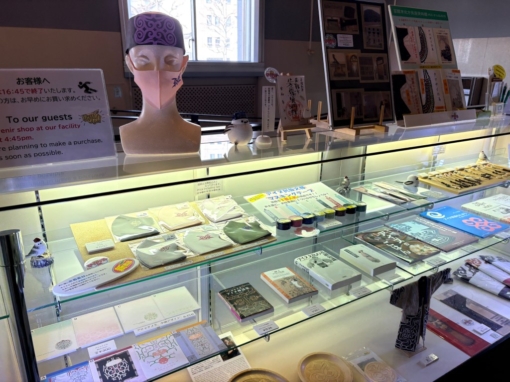 A gift shop display with Ainu pattern masks and bird-themed goods.