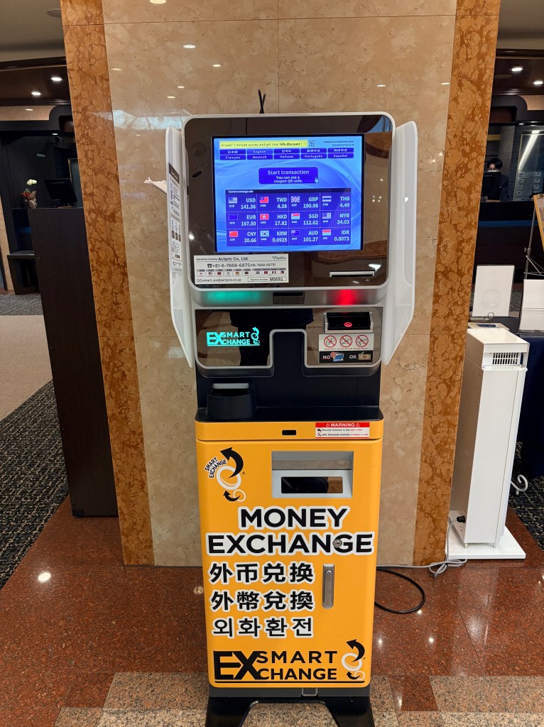 A yellow automated currency exchange machine located in a hotel lobby.