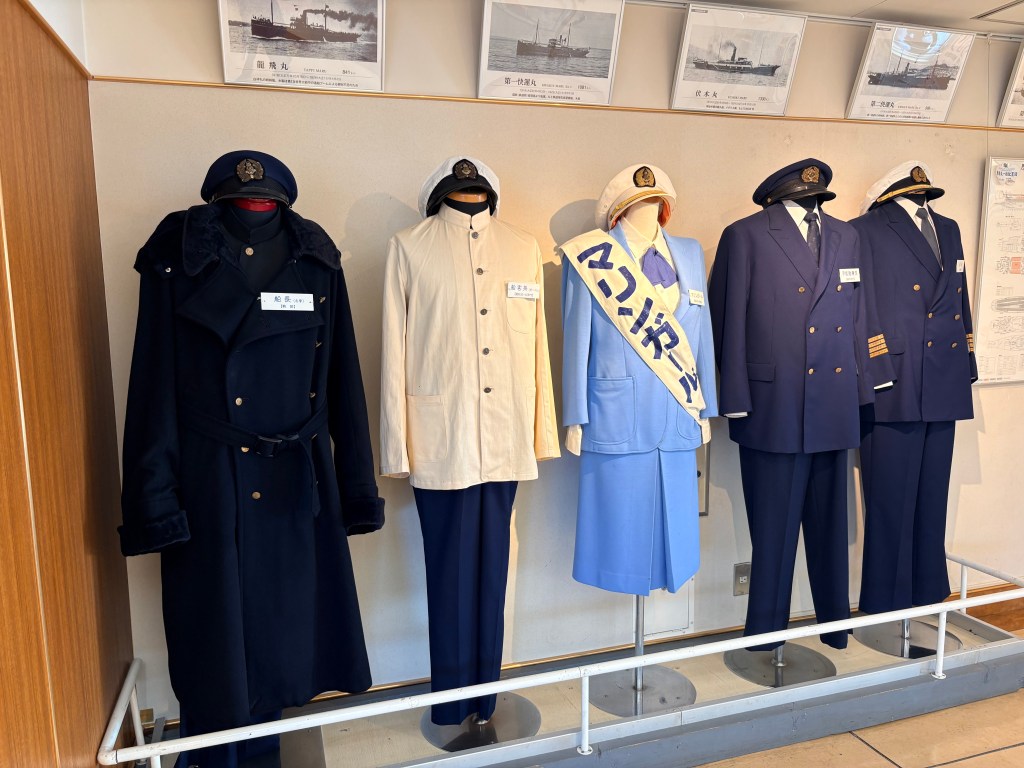 Mannequins wearing various historical Seikan Ferry crew uniforms in navy and white on display.