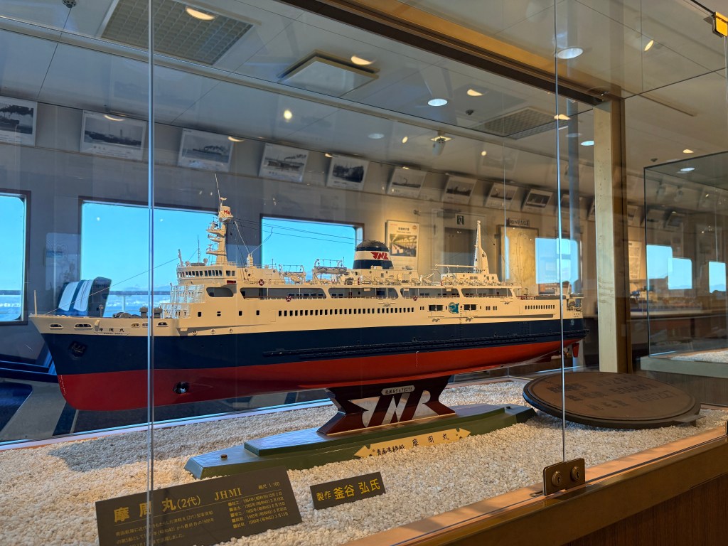 A detailed scale model of the second Mashu Maru displayed in a glass case.