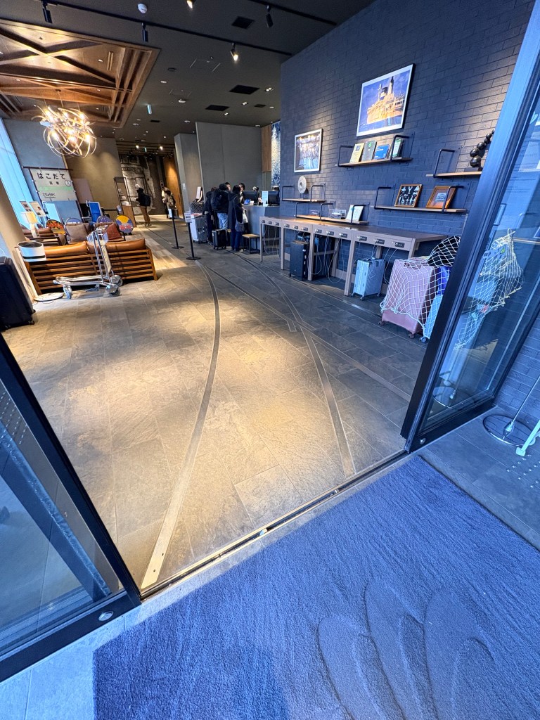 A close-up shot looking down at the hotel lobby floor, which has embedded metal rails and wooden sleepers designed to look exactly like a railroad track.