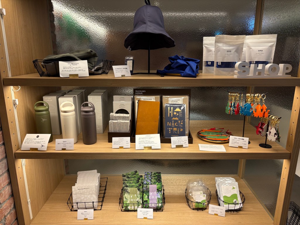 A focused shot of wooden shelving units in the hotel lobby, neatly stacked with various colorful items like towels, bags, and local food products.