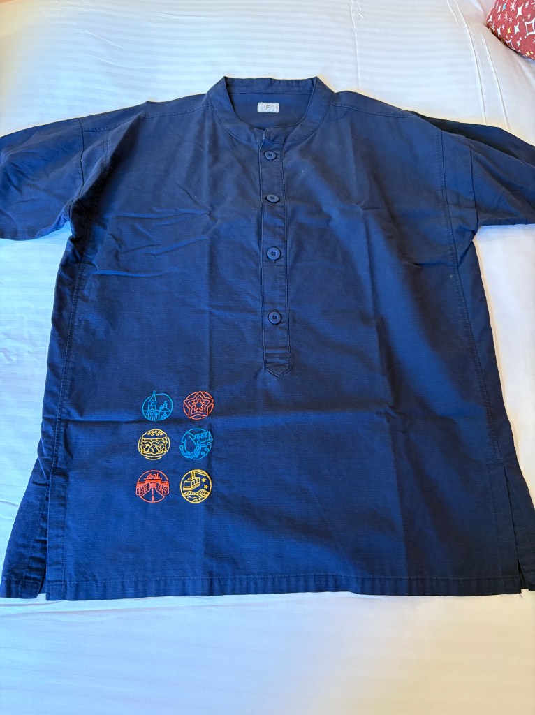 A set of brown, waffle-textured one-piece hotel pajamas laid out neatly on a white bed.