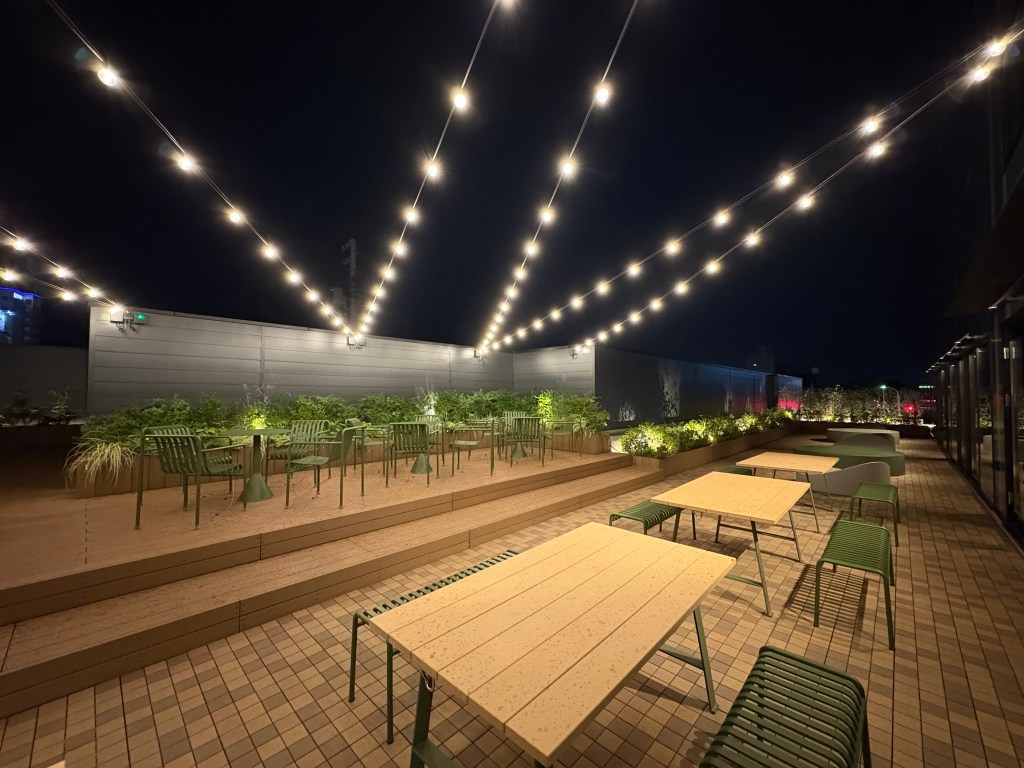 View from inside the hotel relaxation lounge, looking out through floor-to-ceiling windows at the city of Hakodate and the surrounding mountains.