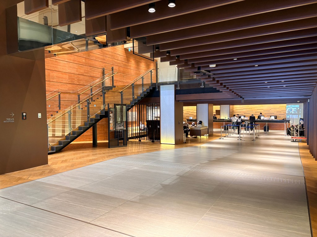 Front desk and reception counter area in the Hakodate Kokusai Hotel lobby, featuring dedicated check-in lanes and a grand staircase.