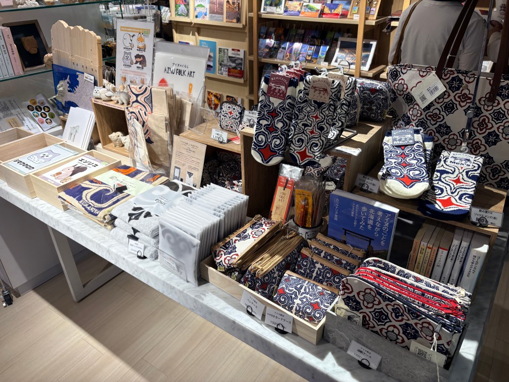 Display of traditional Ainu pattern pouches, socks, handkerchiefs, and regional Hokkaido souvenirs in the hotel shop.